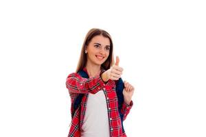 young cheerful brunette student girl with backpack on her shoulders showing thumbs up isolated on white background photo