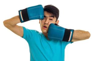 portrait of funny brunette sports man practicing box in blue gloves isolated on white background photo