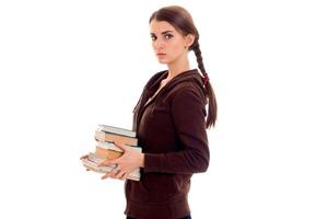 young girl with thoughtful person stands sideways and holding books photo
