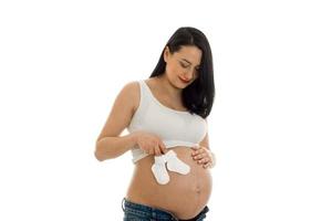 a young pregnant woman holding a little baby shoes isolated on white background photo