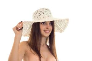 Chica joven sexy en el sombrero mira hacia otro lado y sonriendo aislado sobre fondo blanco. foto