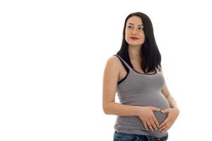 young pregnant girl with dark hair touching her big belly and looking aside isolated on white background photo
