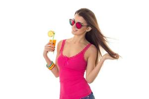 hermosa chica moldaja con una camiseta brillante y gafas de sol se pone de lado y sostiene un vaso de jugo foto