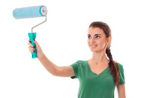 young cute girl holding a roller for painting and smiling photo