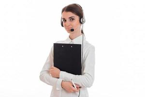 beautiful young girl in headphones and a white shirt looks into the camera and holds black Tablet photo