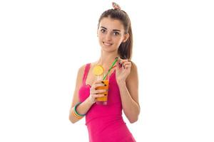 hermosa joven con una camisa rosa sonriendo y sosteniendo un vaso de jugo de fruta foto