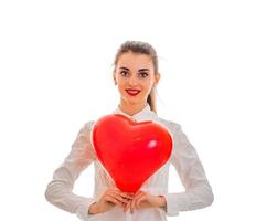 charming young brunette woman with red lips and heart in her hands posing isolated on white background photo