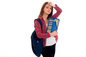 Encantadora joven estudiante morena adolescente con ropa elegante y mochila sobre los hombros posando aislada de fondo blanco foto