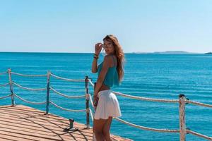 joven rubia posando en el muelle con fondo marino foto