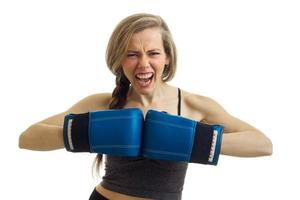 a young athletic girl screams and holds hands in boxing gloves before of isolated on white background photo