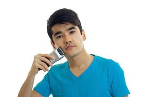 handsome young guy in a t-shirt shaves shaving machines using photo