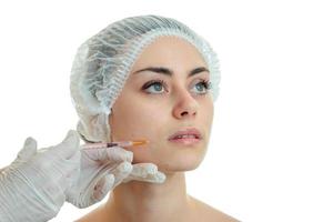 Portrait of a young girl at the doctor who makes an analgesic injection on the face in white gloves close-up photo