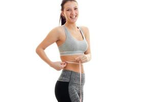 smiling attractive fitness girl takes the waist measuring tape photo