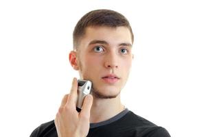 Portrait of a charismatic guy who shaves his beard trimmer close-up photo