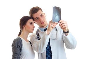 cute young girl standing next to a doctor in a white lab coat and he shows her an x-ray photo