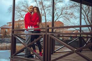 una encantadora pareja joven enamorada se abraza en un balcón en invierno foto