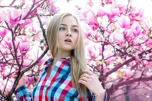 hermosa chica sensible cerca del floreciente árbol rosa foto