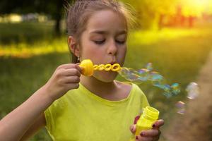 retrato de una niña linda con pompas de jabón en un día soleado foto