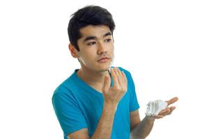attractive young guy with black hair on his face shaving foam hands photo