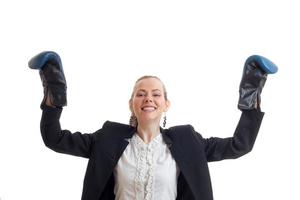 mujer de negocios alegre y fuerte con uniforme clásico con guantes de boxeo y manos en el aire