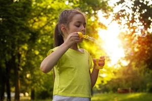 little girl standing on the street and inflates soap-bubbles photo