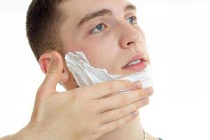 close up portrait of young handsome man with shaving cream on his face photo