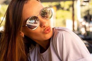 charming girl in sunglasses gives an air kiss photo