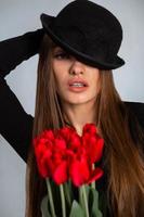 portrait of a beautiful girl in a hat with tulips in hands photo