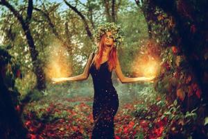 elegante bruja chica pelirroja conjura en el bosque mágico foto