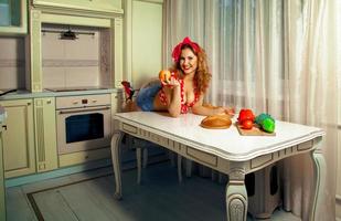 Horizontal portrait of sexual young woman posing on table in the kitchen photo