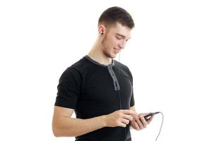 Portrait of a young handsome guy in a t-shirt with a phone in hands photo