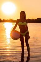 adorable slim lady in swimsuit with beach ball in the sea photo