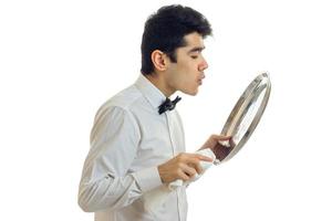 the young waiter stands sideways and blowing on a tray in the hands of a close-up photo