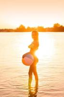 adorable slim lady in swimsuit with beach ball in the sea photo