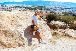 hombre con gafas de sol mira la vista de la ciudad desde la colina alta foto