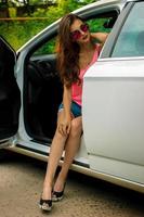 vertical portrait of fashionable girl in glasses sitting in the car photo