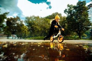 Cutie Little Girl paseos a través de los charcos en bicicleta en el parque foto
