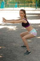 Cheerful slim girl makes sport exercises and smiles on camera photo