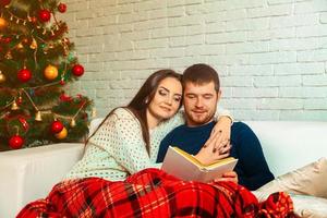 atractiva pareja joven lee una historia de navidad foto