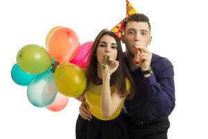 Cheerful young couple with horns and balloons celebrate a birthday photo