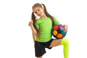 Cheerful girl with soccer ball shows thumbs up and smiles photo