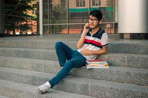 young student sitting on the stairs with books and tolls for telephone photo