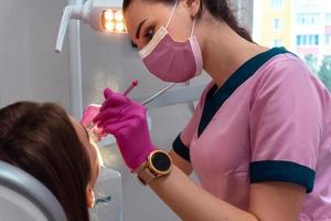 dentista con uniforme rosa trata los dientes de un paciente foto