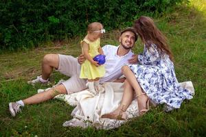 Happy family having fun at the park. Parents with daughter relaxing outdoors. photo