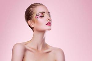 retrato de mujer adulta de belleza con maquillaje profesional creativo sobre fondo rosa foto