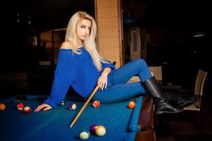 Sexual blonde lady posing on billiard table with the cue photo