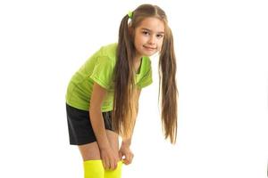 Pretty girl in green soccer uniform posing on camera photo