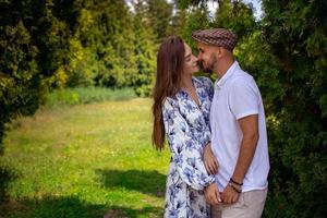 portrait of charming couple in love hugs and holds hands at the green garden photo