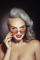 mujer encantadora con buen maquillaje y color de cabello gris con elegantes gafas de sol foto