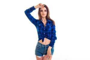 young tender beautiful girl raised her hand to face and stands in front of the camera in a blue shirt and shorts photo